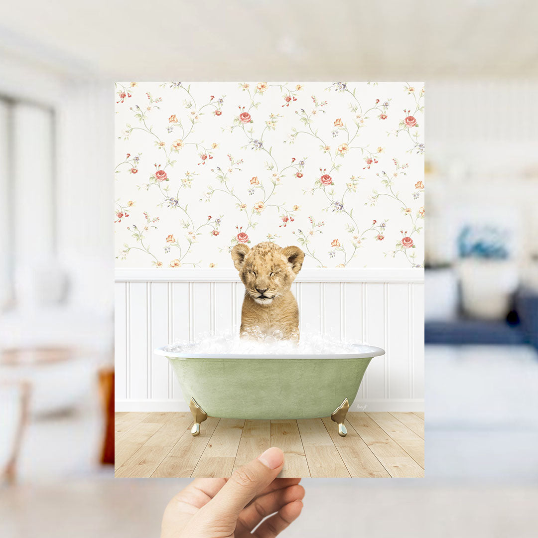 A young lion cub sitting in a green bathtub filled with water, surrounded by a floral wallpaper.