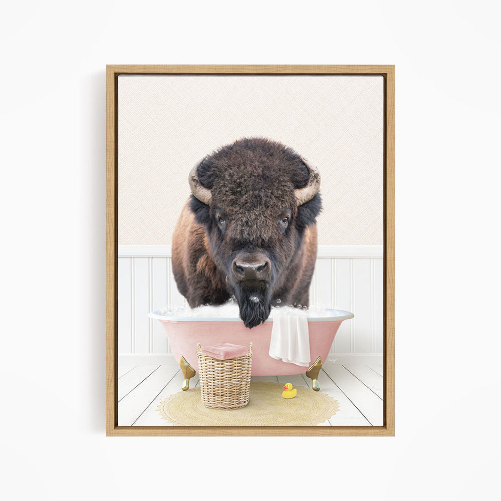 A buffalo standing in a pink bathtub, surrounded by a basket of toys and a towel.