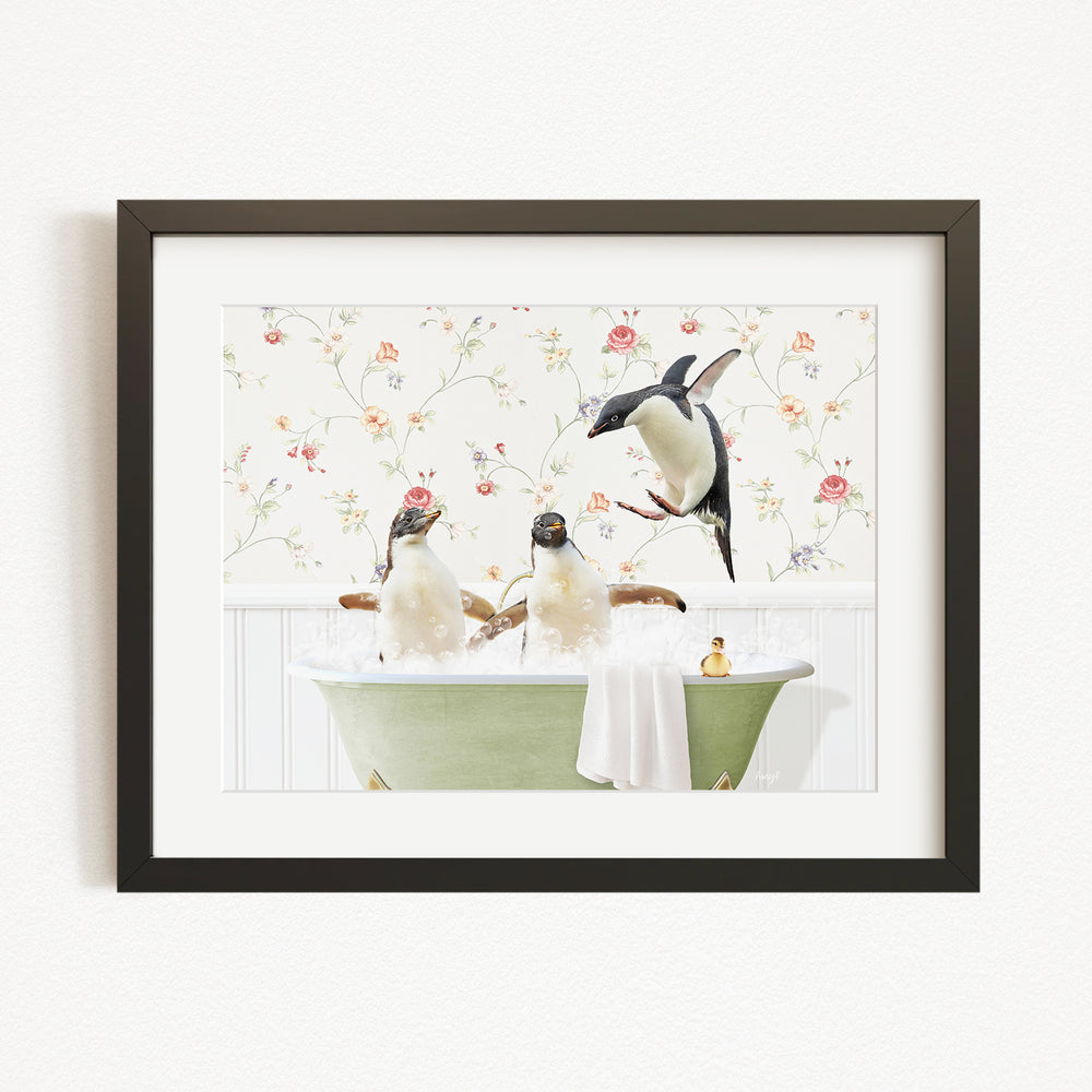 A framed image depicting three penguins sitting in a green bathtub, with one penguin standing on the edge of the tub and another sitting on the side.
