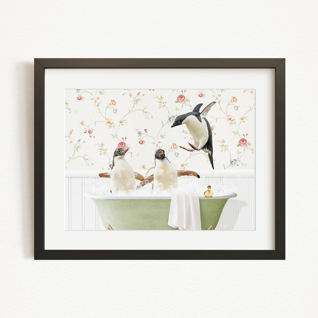 A framed image depicting three penguins sitting in a green bathtub, with one penguin standing on the edge of the tub and another sitting on the side.