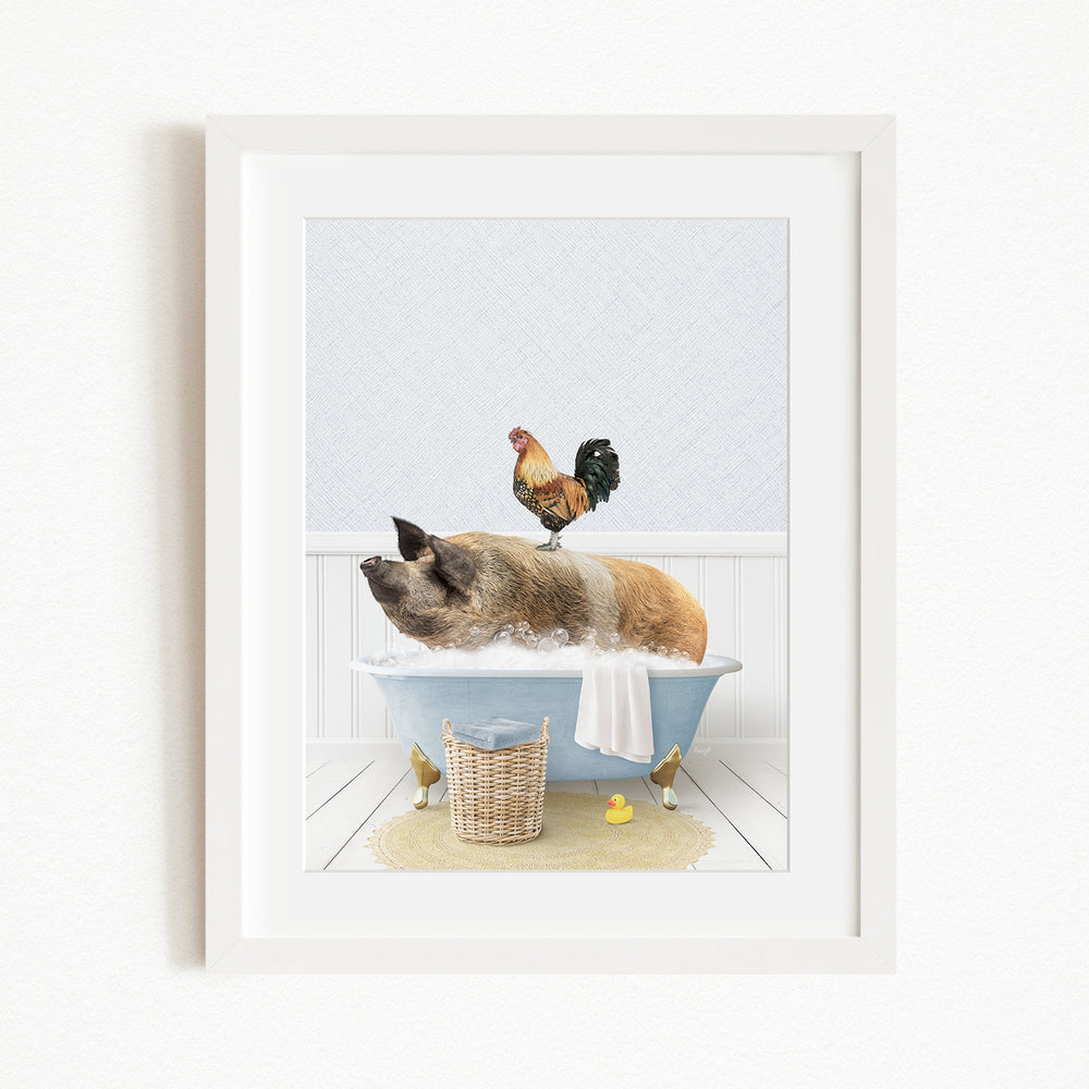A framed image depicting a pig sitting in a bathtub, with a rooster perched on its back, and a basket of rubber ducks nearby.