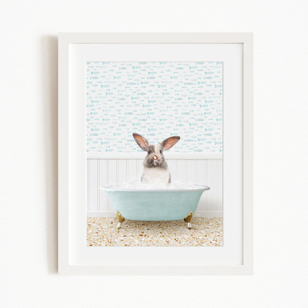 A rabbit sitting in a light blue bathtub filled with bubbles, surrounded by a patterned wall and a beige and white tiled floor.
