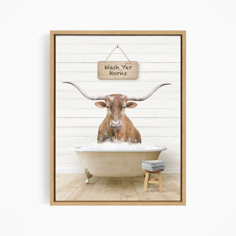 A framed image depicting a bull with large horns sitting in a bathtub, with a sign above that says "Wash Yer Horns".