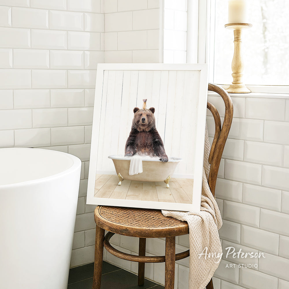 A framed image of a bear sitting in a bathtub, with a towel draped over the side of the tub.
