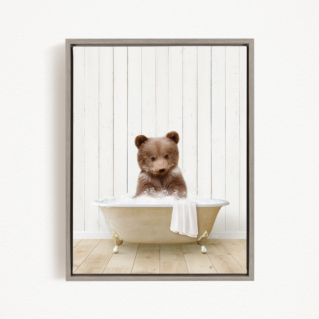 A brown bear sitting in a white bathtub filled with water, looking directly at the camera.