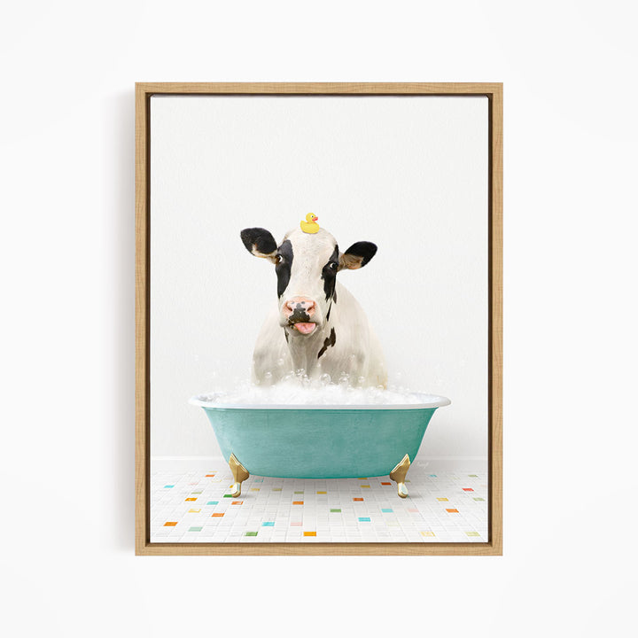 A black and white cow is sitting in a blue bathtub filled with bubbles, with a yellow rubber duck perched on its head.