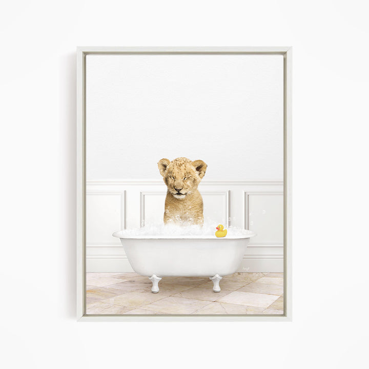 A young lion cub is sitting in a white bathtub filled with water, surrounded by a yellow rubber duck.