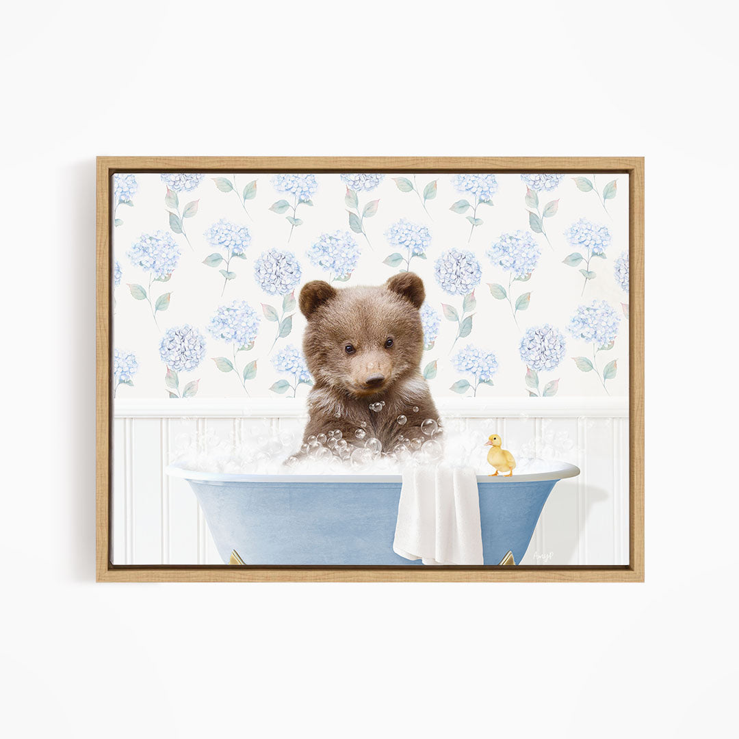 A brown bear sitting in a blue bathtub filled with bubbles, with a yellow rubber duck floating nearby.
