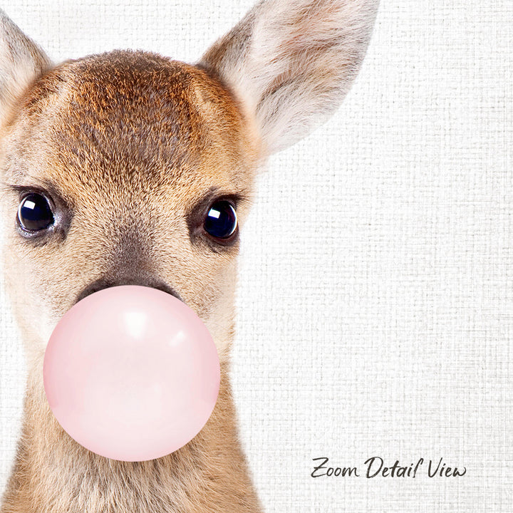 A deer with a pink bubble gum bubble in its mouth, looking directly at the camera.
