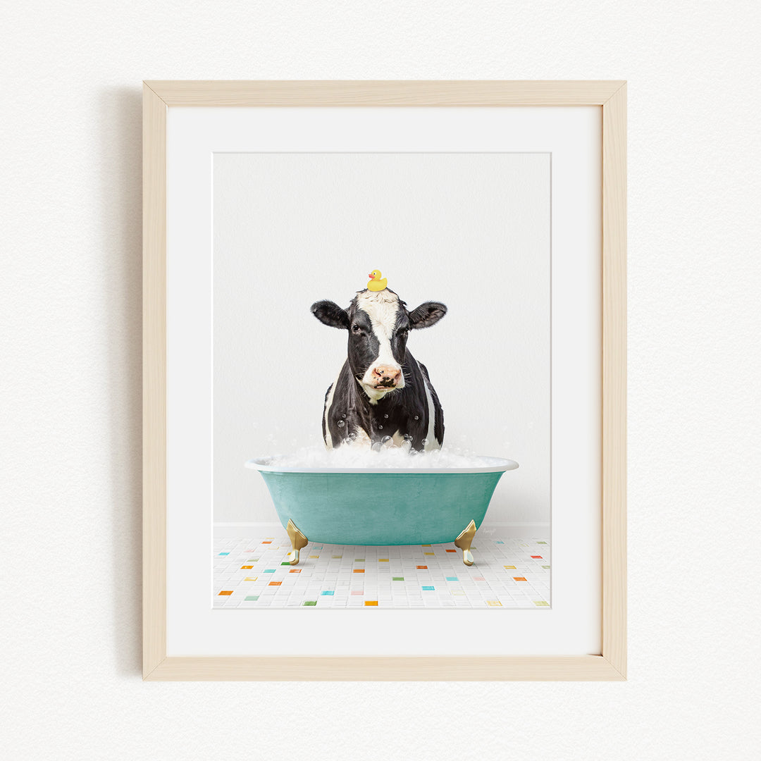 A black and white cow is sitting in a green bathtub filled with bubbles, with two yellow birds perched on its head.