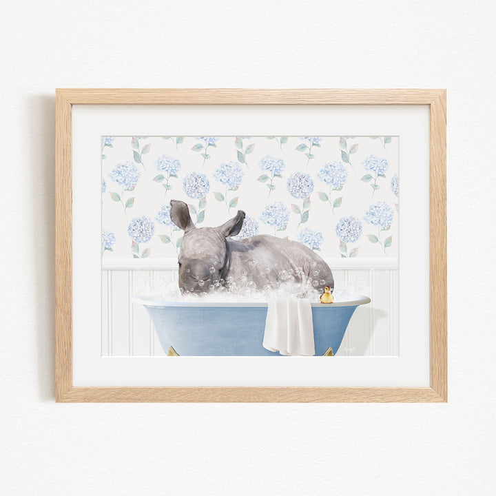 A rhinoceros is sitting in a blue bathtub filled with water, surrounded by a floral pattern on the wall behind it.