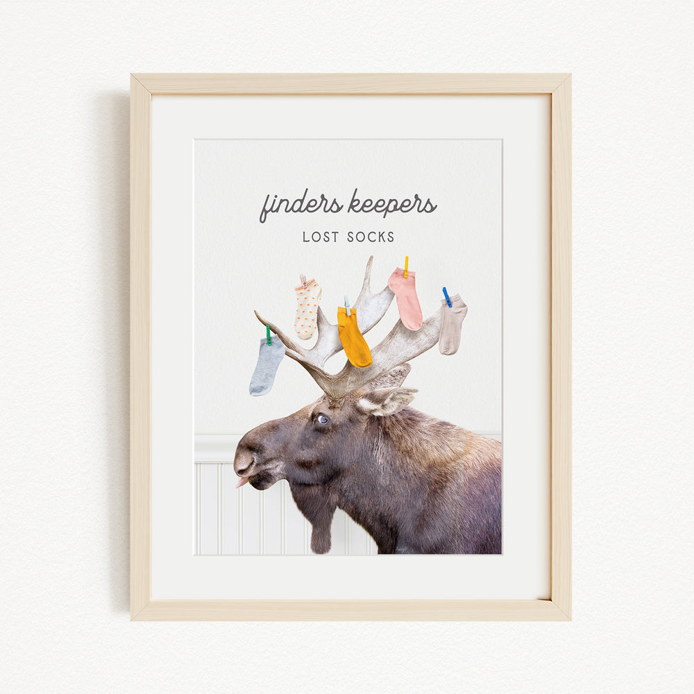 A framed image of a moose with a pile of colorful socks on its head, accompanied by the text "finders keepers lost socks"