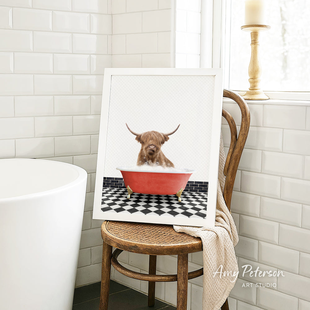 A framed image of a Highland cow sitting in a red bathtub, with a black and white checkered floor in the background.