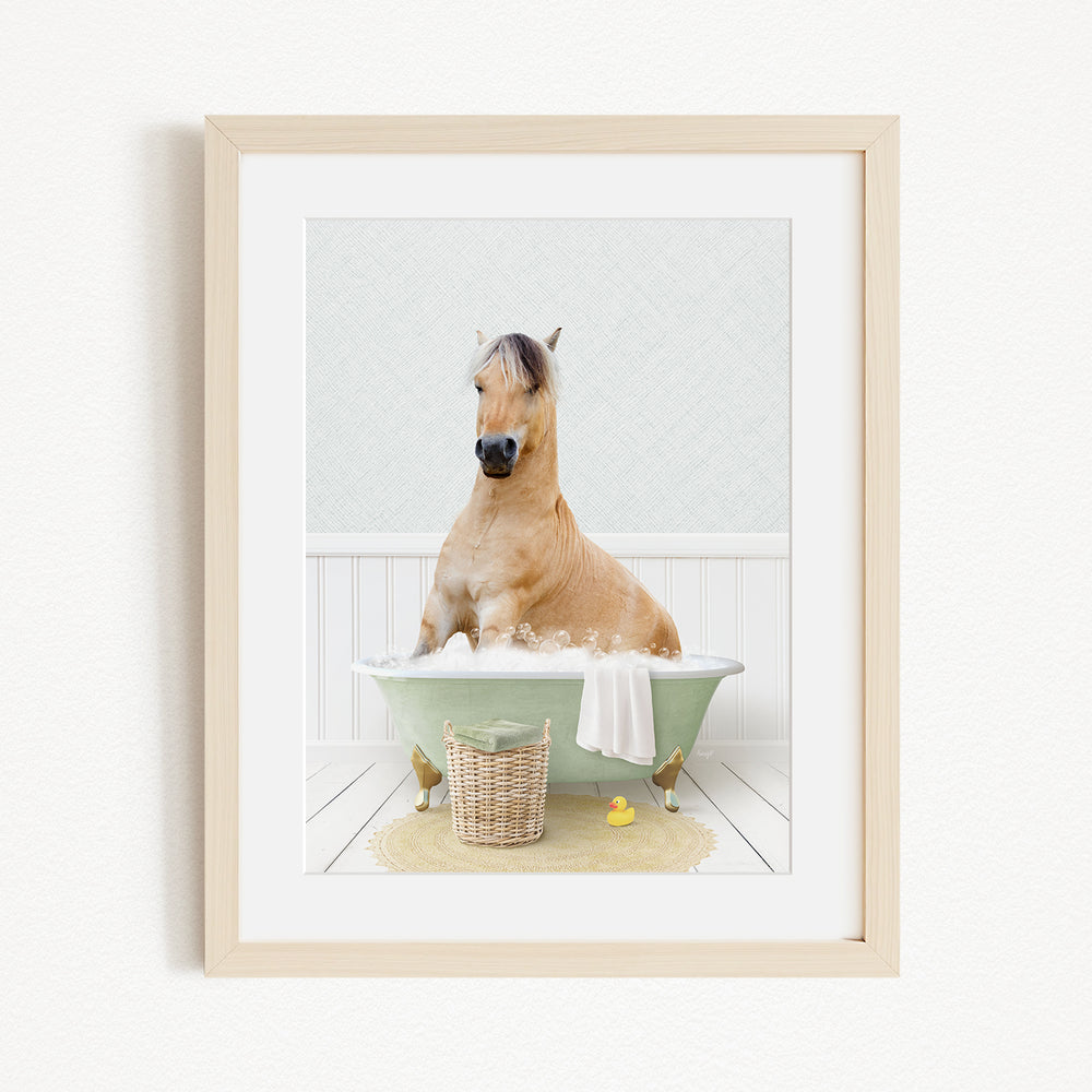 A light brown horse is sitting in a green bathtub filled with water, surrounded by a yellow rubber duck and a basket.