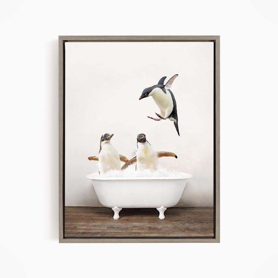 A framed image depicting three penguins sitting in a white bathtub, with one penguin flying towards the tub.