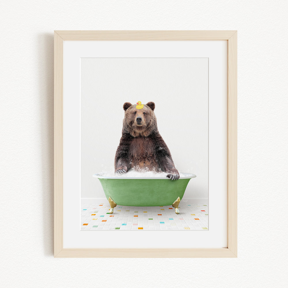 A brown bear sitting in a green bathtub filled with bubbles, with a yellow rubber duck floating on the water.