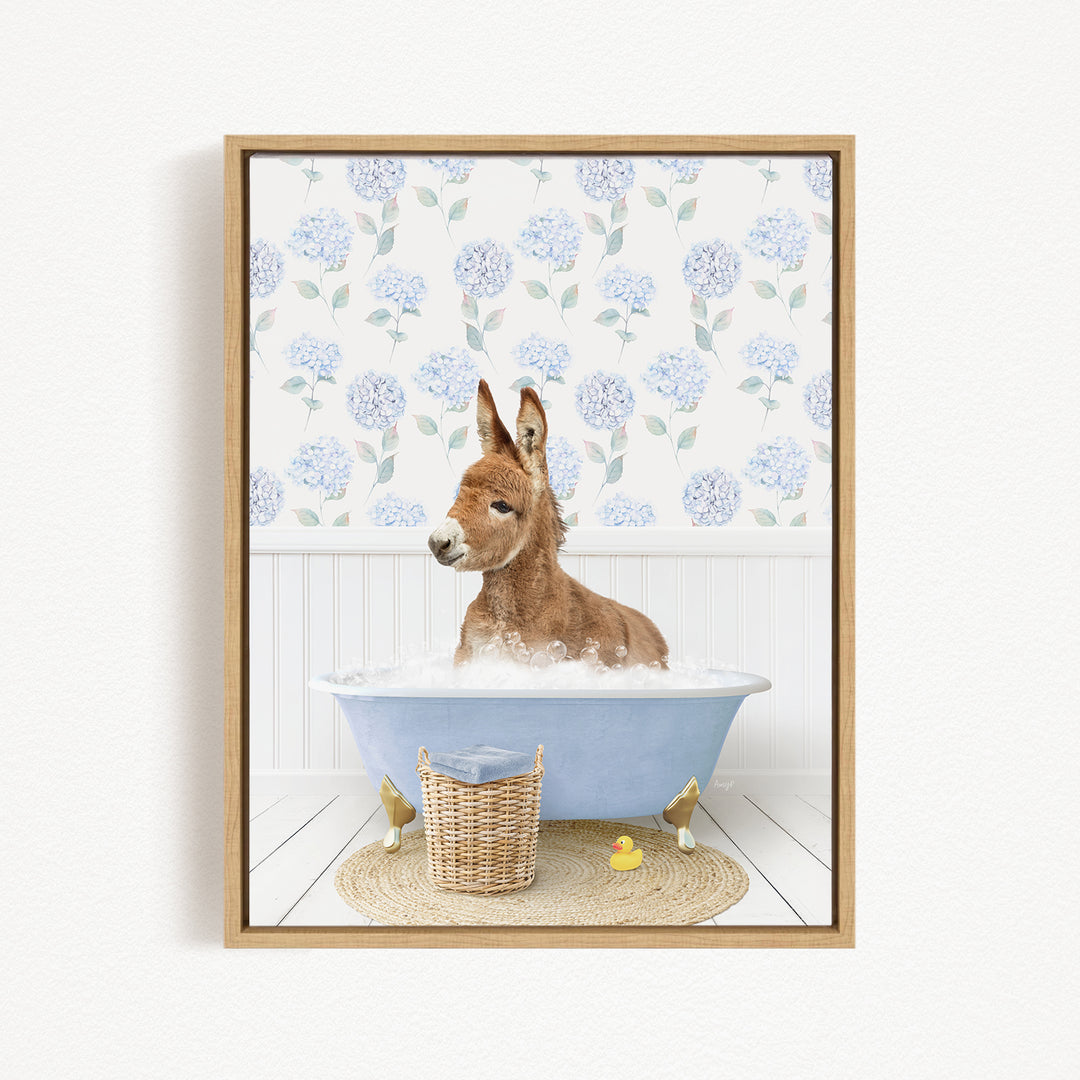 A donkey is sitting in a blue bathtub filled with water, surrounded by a wicker basket and two rubber ducks.