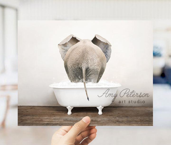 a person holding up a card with an elephant in a bathtub