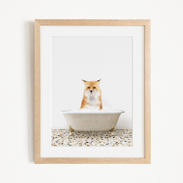 A red fox sitting in a white bathtub filled with water, looking directly at the camera.