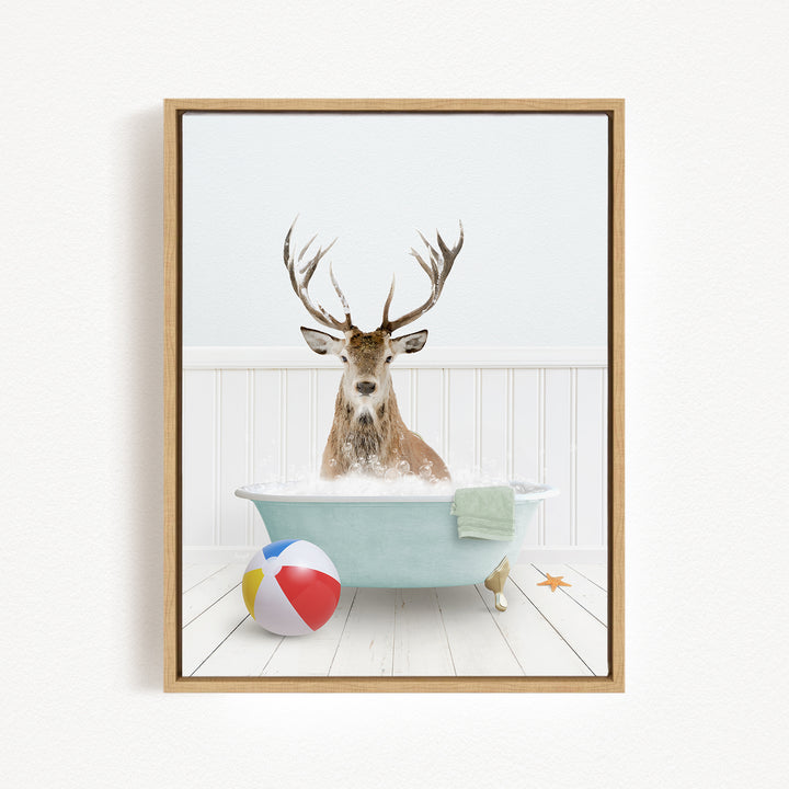 A deer with antlers is sitting in a bathtub filled with water, surrounded by a beach ball and a towel.