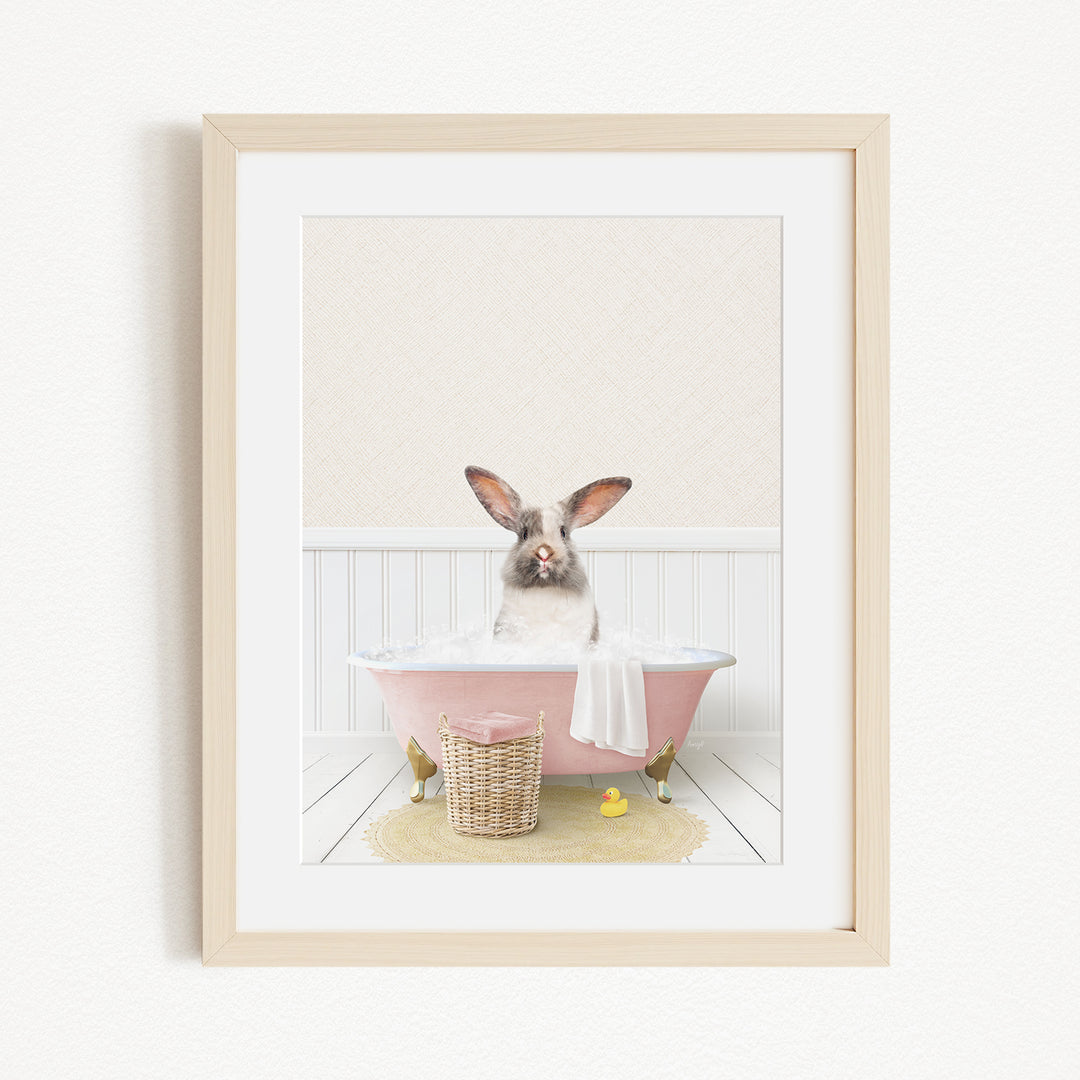 A rabbit sitting in a pink bathtub filled with water, surrounded by a yellow rubber duck and a basket.