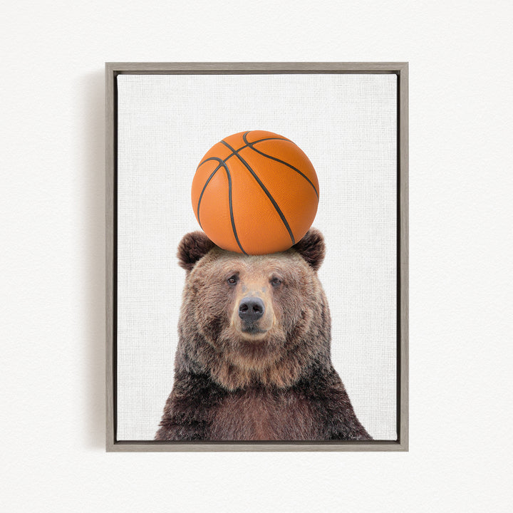 A brown bear balancing a basketball on its head.