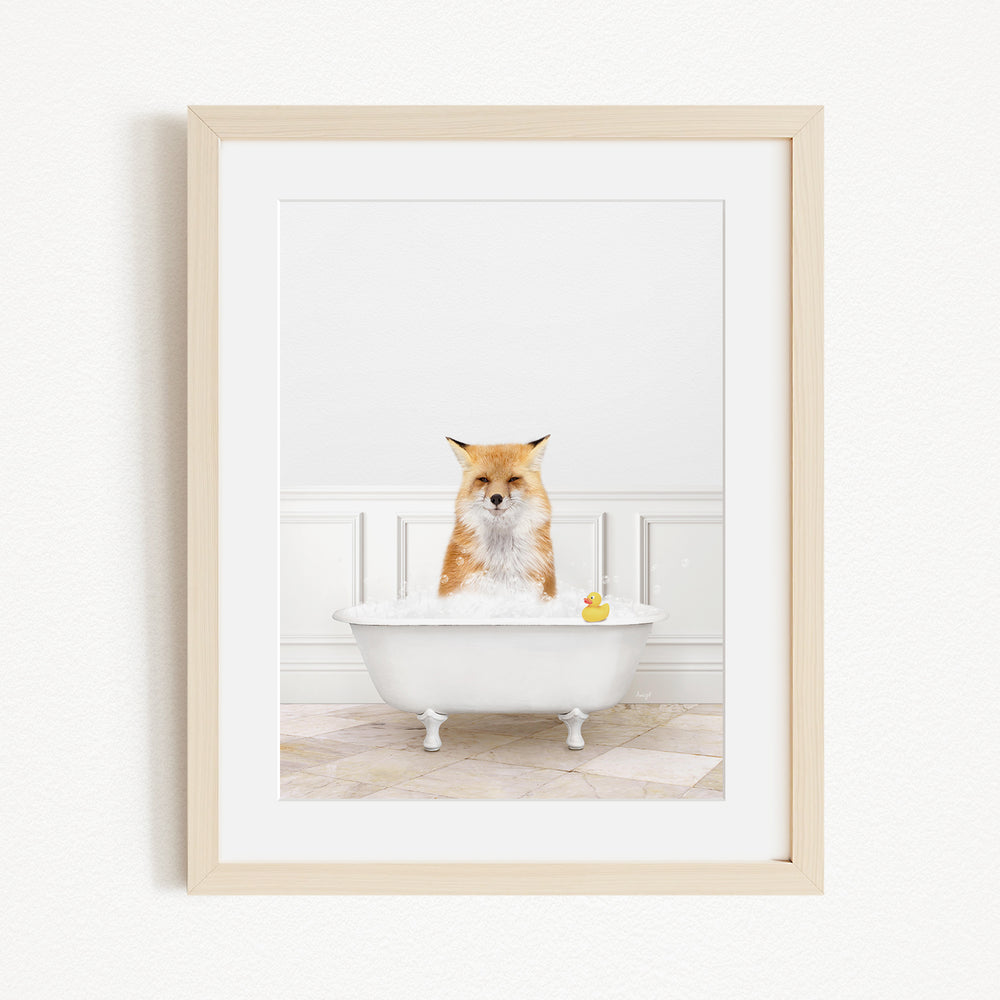 A red fox is sitting in a white bathtub filled with bubbles, with a yellow rubber duck floating in the water.