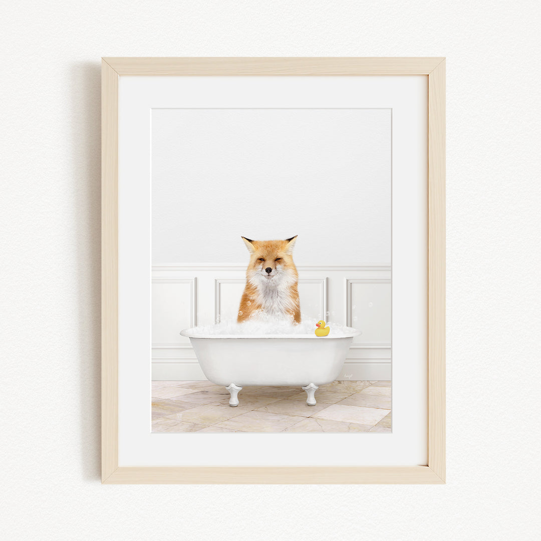 A red fox is sitting in a white bathtub filled with bubbles, with a yellow rubber duck floating in the water.