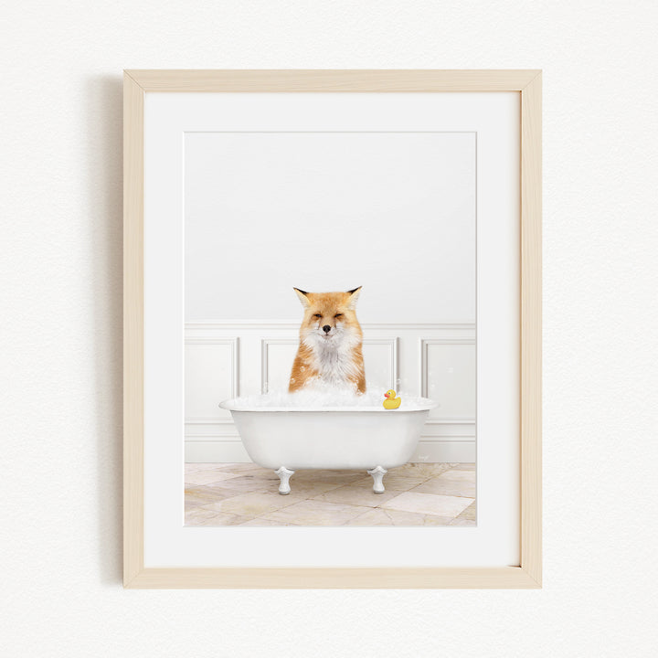 A red fox is sitting in a white bathtub filled with bubbles, with a yellow rubber duck floating in the water.