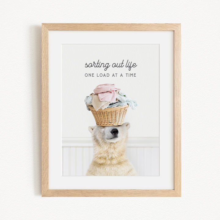 A polar bear balancing a basket of laundry on its head, with the text "sorting out life" above the basket.