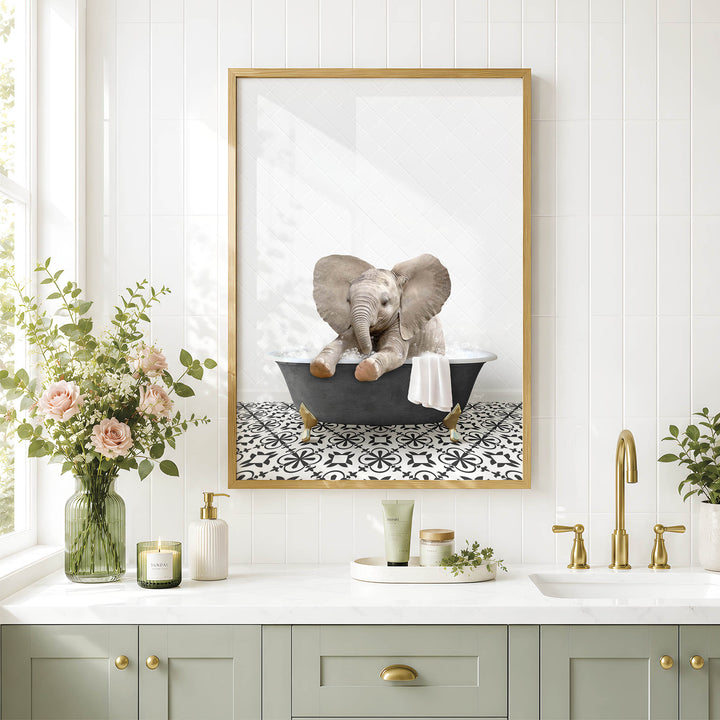 A framed image of an elephant sitting in a bathtub is displayed on a wall above a bathroom counter with various toiletries and a vase of flowers.