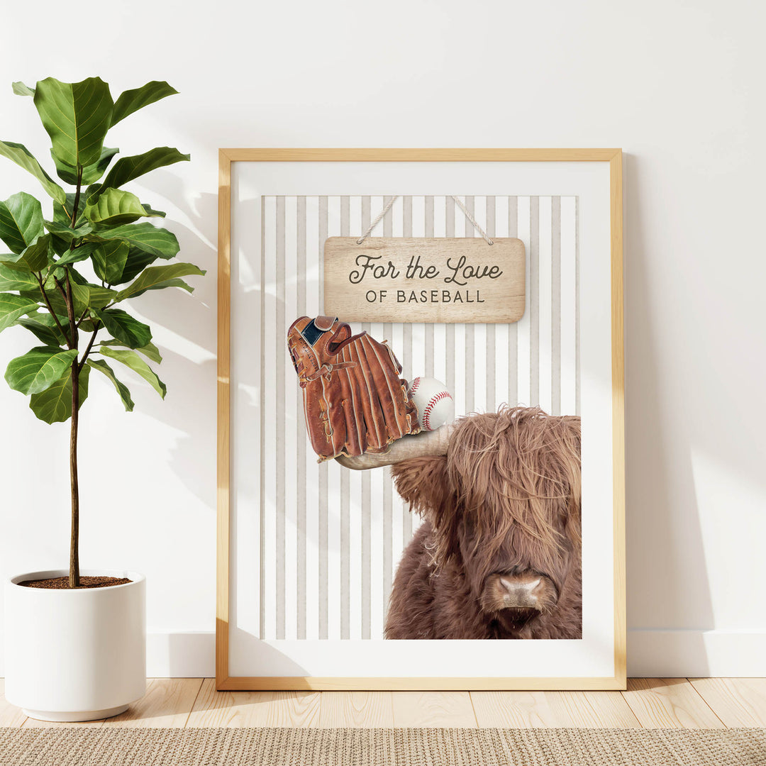 a framed print of a cow with baseball gloves on its horns, accompanied by a wooden sign that reads "For the Love of Baseball".