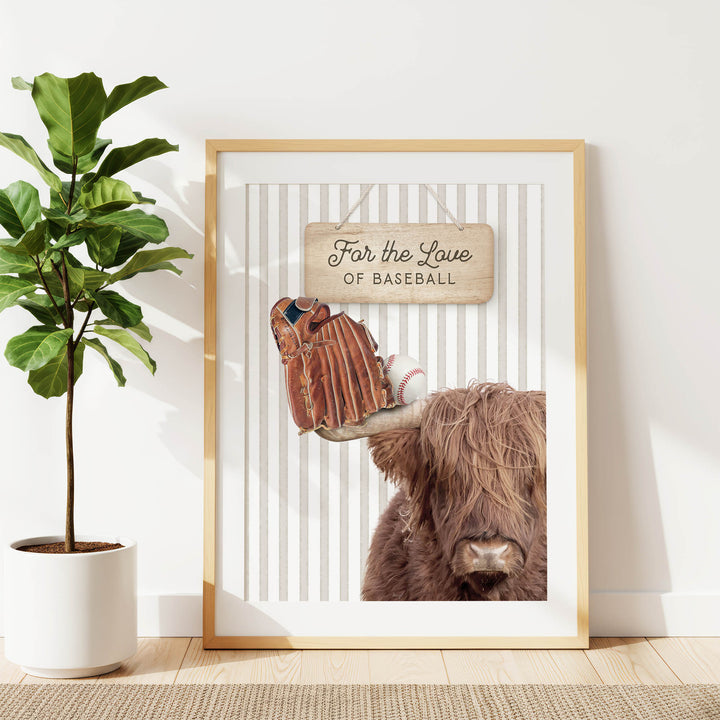 a framed print of a cow with baseball gloves on its horns, accompanied by a wooden sign that reads "For the Love of Baseball".