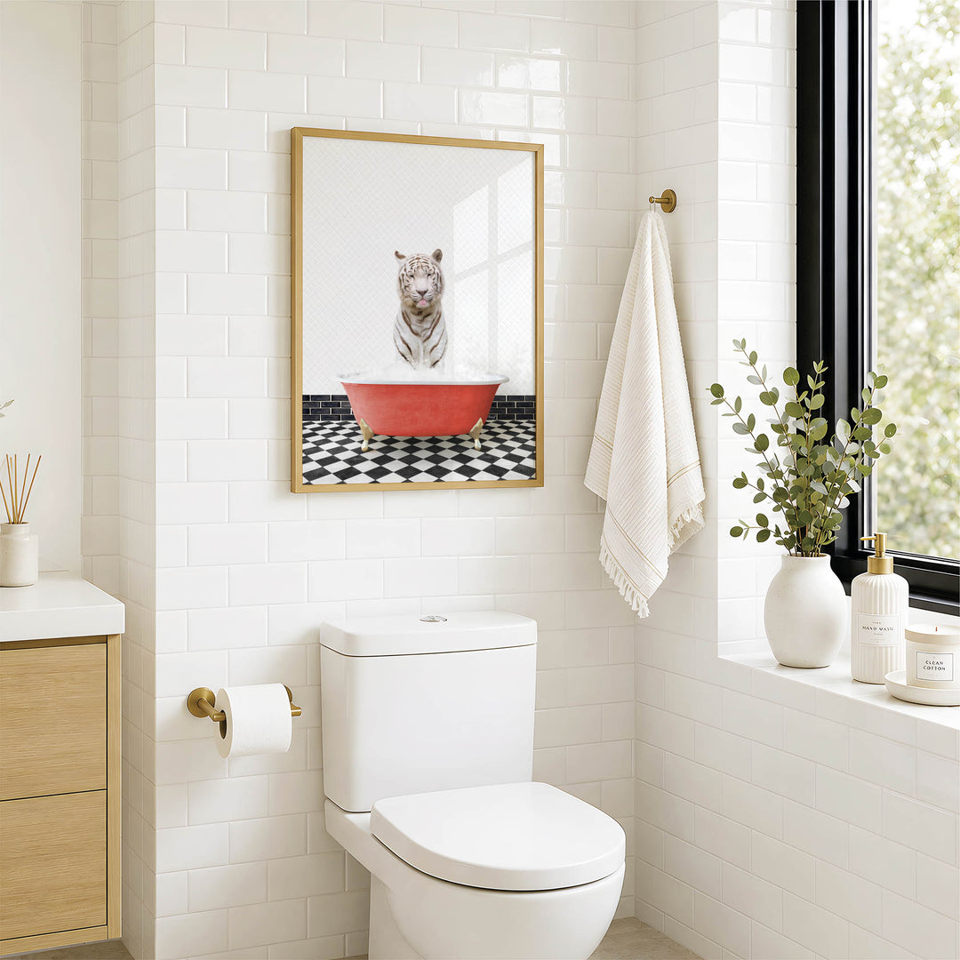 A bathroom with a white toilet, a framed picture of a tiger sitting in a red bathtub, and a window with greenery outside.