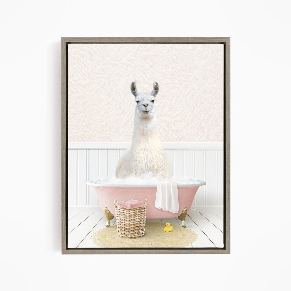 A white llama sitting in a pink bathtub filled with bubbles, surrounded by a yellow rubber duck and a wicker basket.