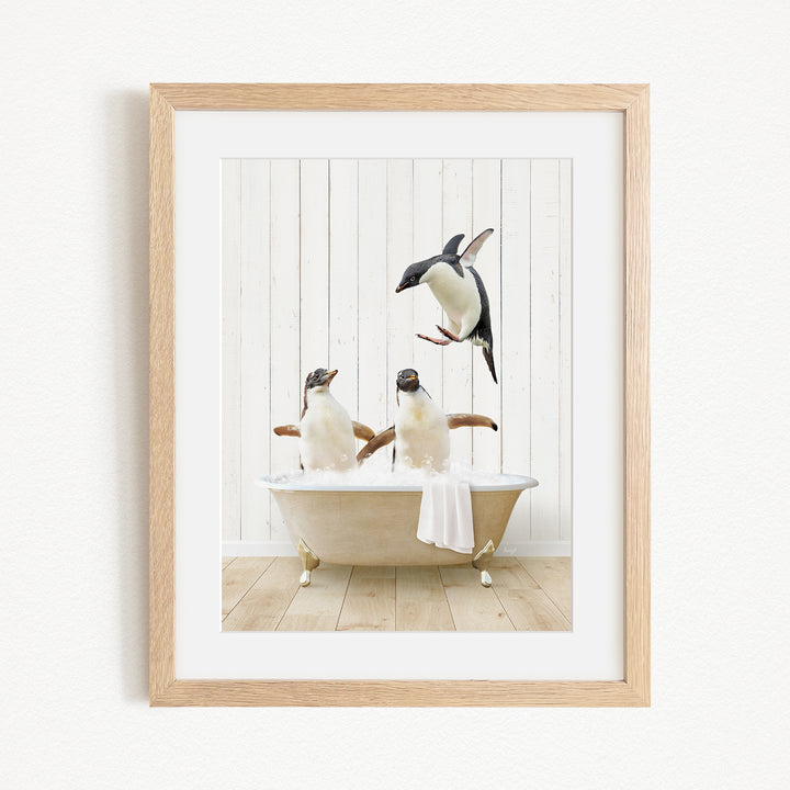 A framed image depicting two penguins sitting in a bathtub, with one penguin flying towards the other penguin.