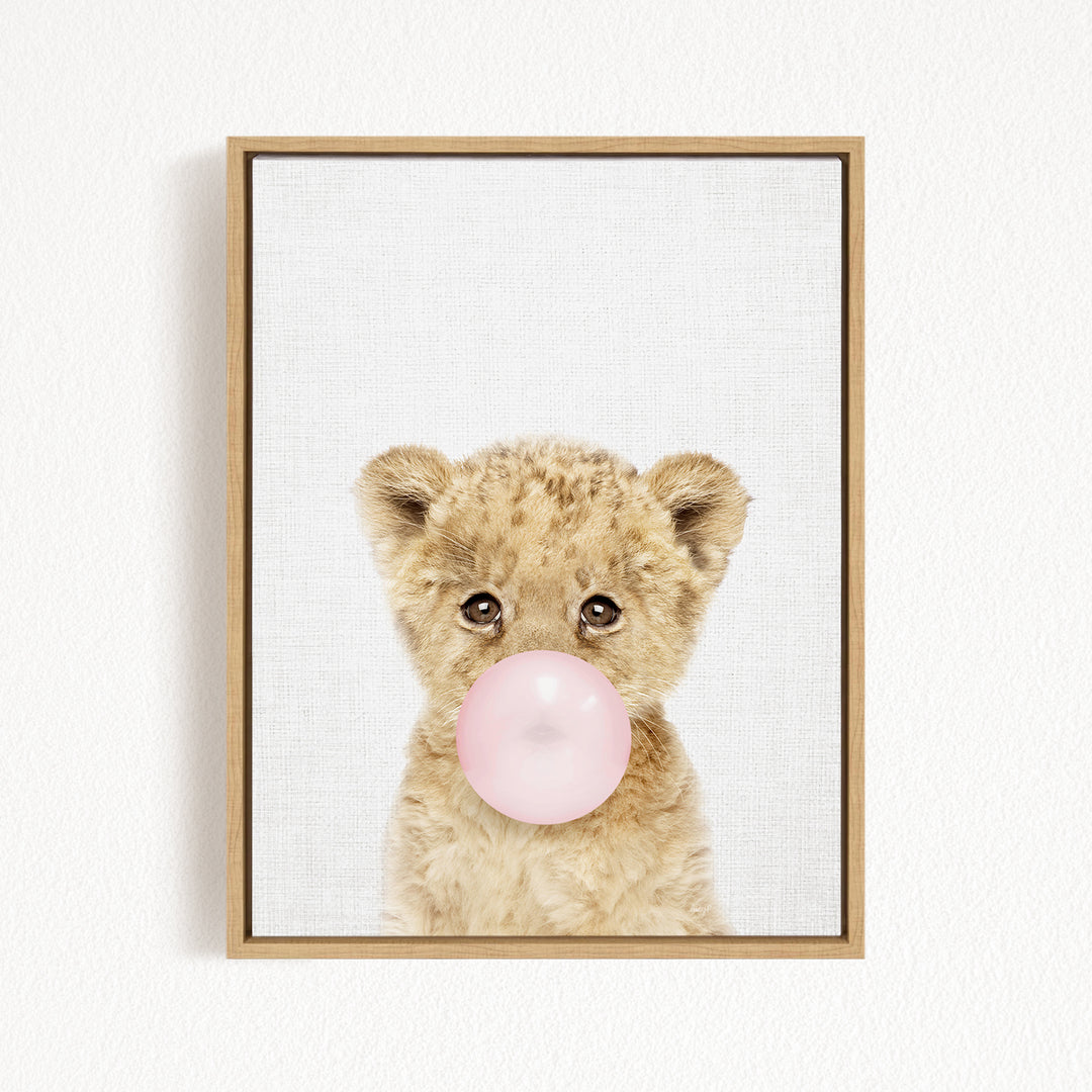 A cute baby lion blowing a bubble with a pink bubble gum bubble.