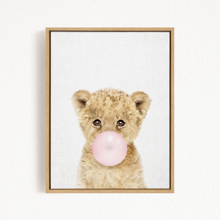 A cute baby lion blowing a bubble with a pink bubble gum bubble.