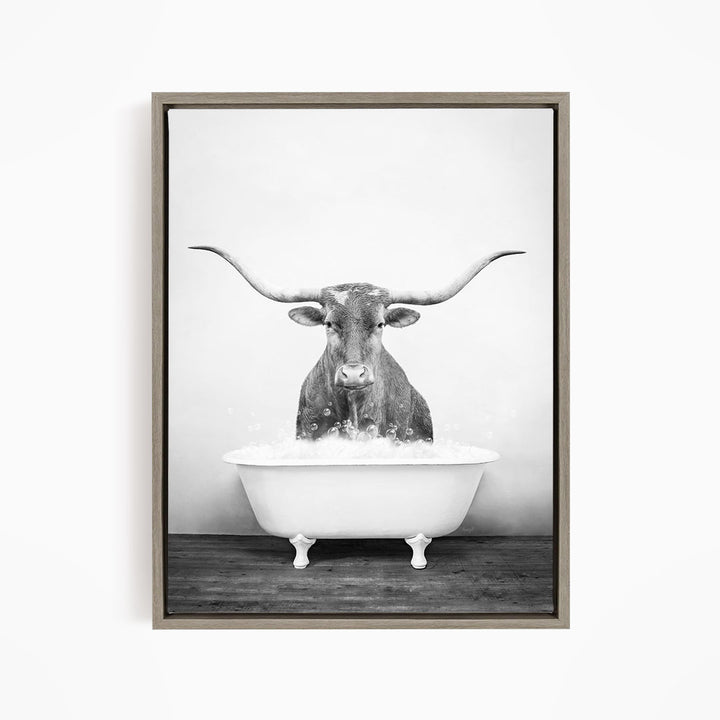 A black and white image of a bull with long horns standing in a bathtub filled with water.