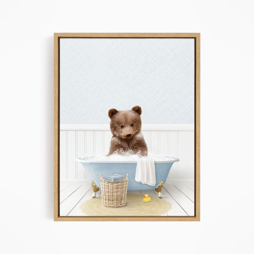 A brown bear sitting in a blue bathtub filled with bubbles, surrounded by a yellow rubber duck and a basket.