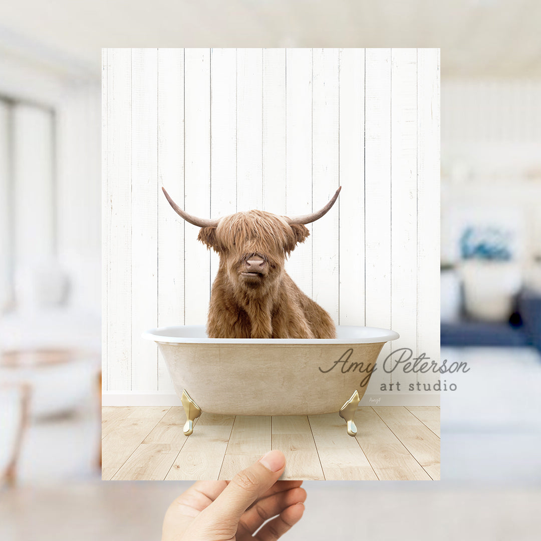 a hand holding a photo of a brown cow in a bathtub