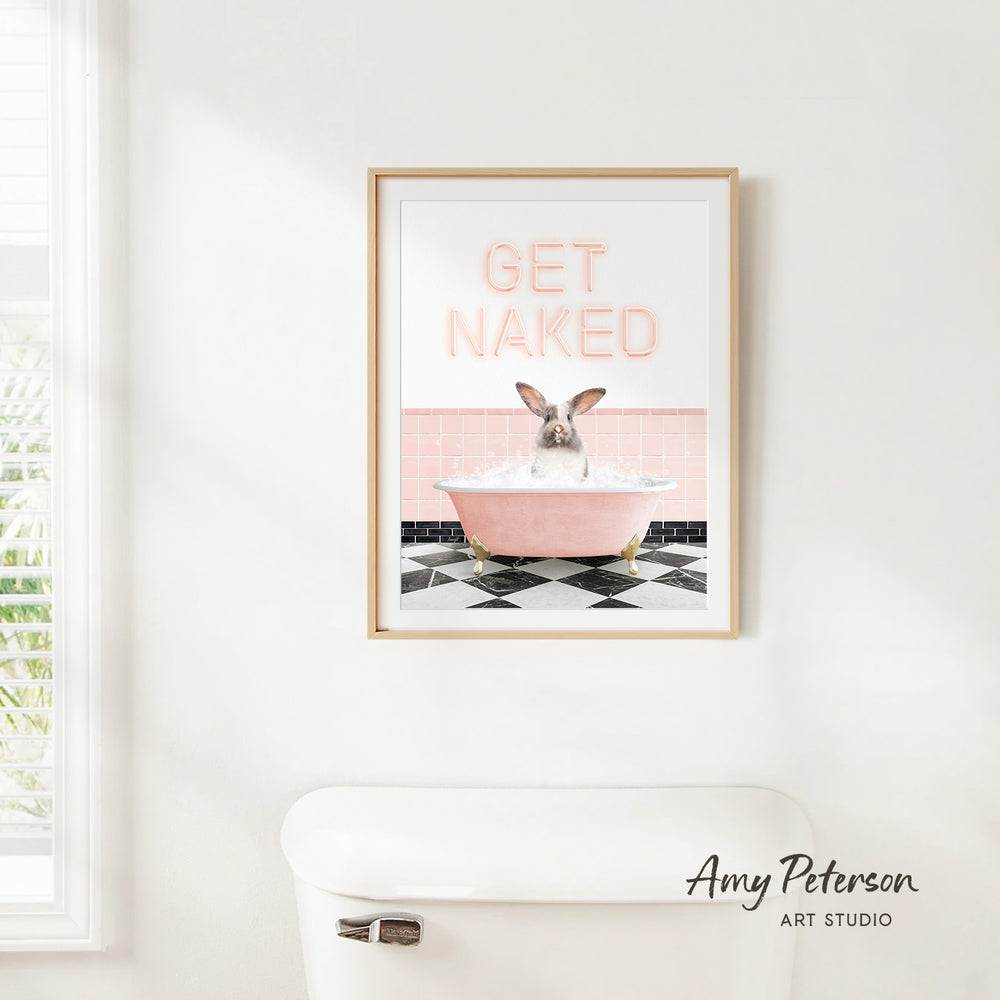 A framed poster with the text "GET NAKED" and an image of a rabbit sitting in a pink bathtub.