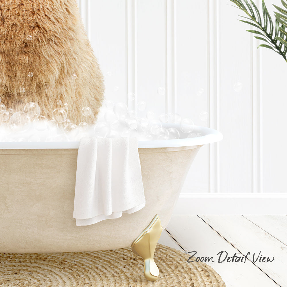 A fluffy brown cat sitting in a white bathtub filled with bubbles, with a towel and gold bathtub leg visible.