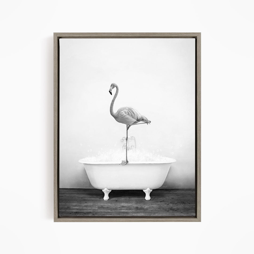A black and white photograph of a flamingo standing on the edge of a white bathtub filled with water.