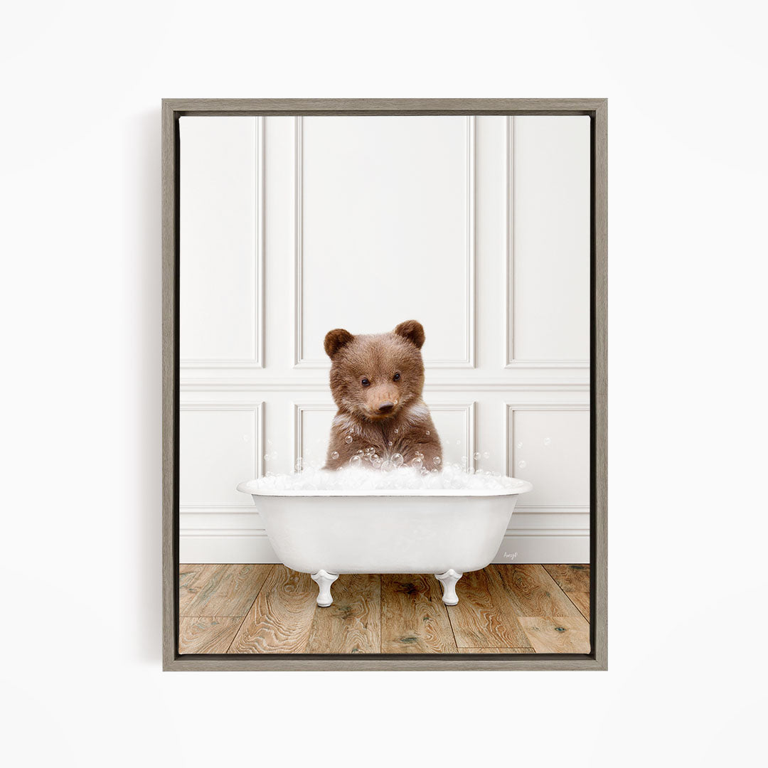 A brown bear sitting in a white bathtub filled with bubbles, looking directly at the camera.