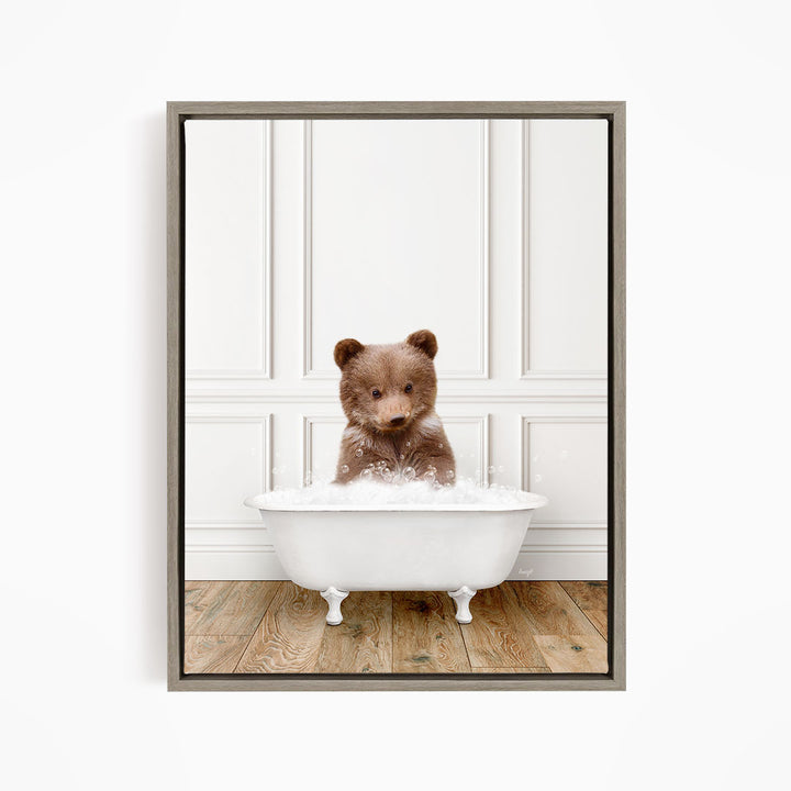 A brown bear sitting in a white bathtub filled with bubbles, looking directly at the camera.