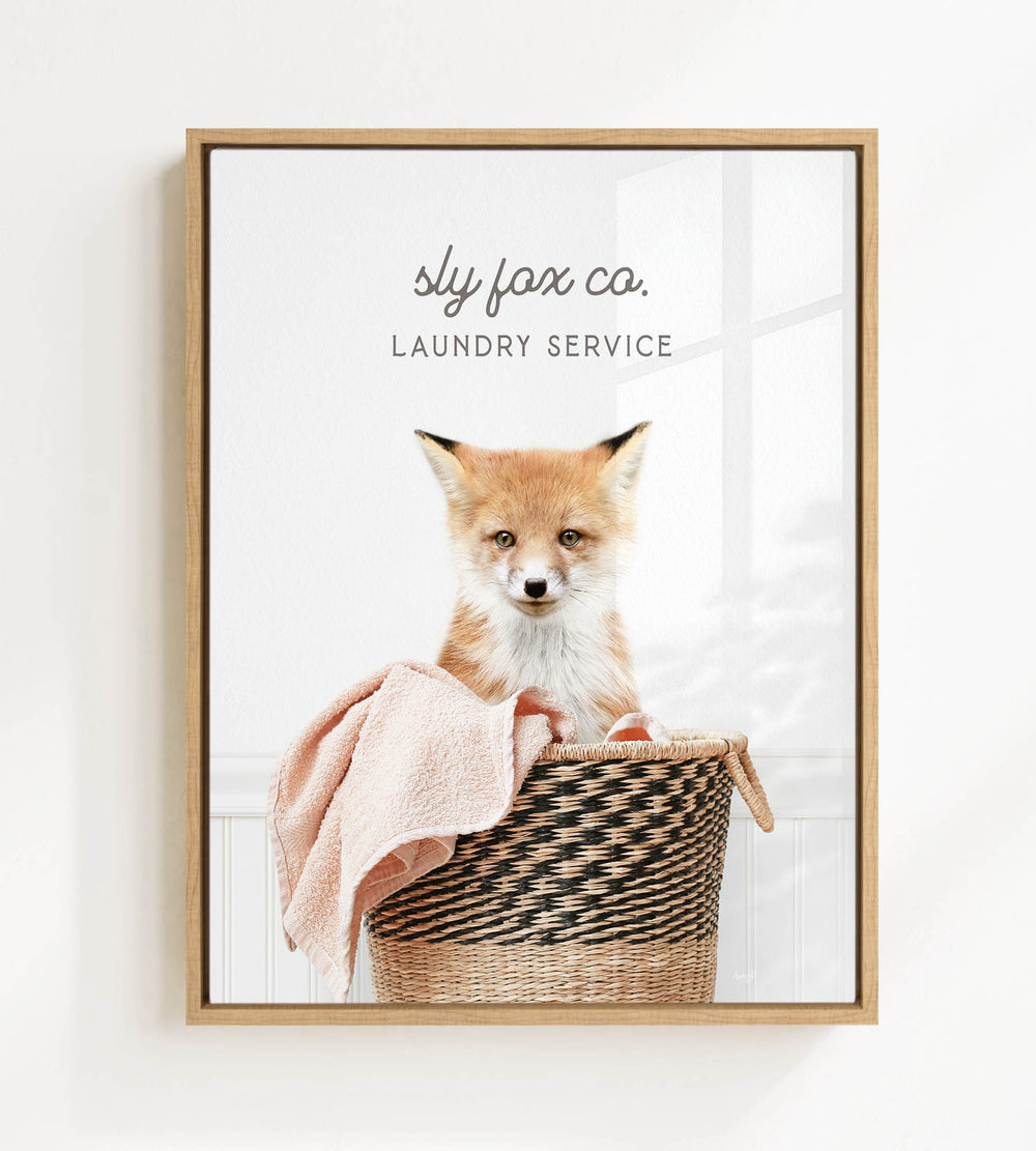 A young fox sits in a woven laundry basket, with a towel draped over its back.
