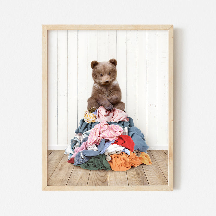 a brown teddy bear sitting on top of a pile of clothes