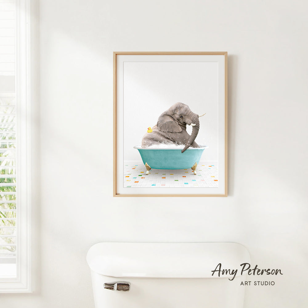 A framed watercolor painting of a gray elephant sitting in a blue bathtub, with a yellow rubber duck floating in the water.