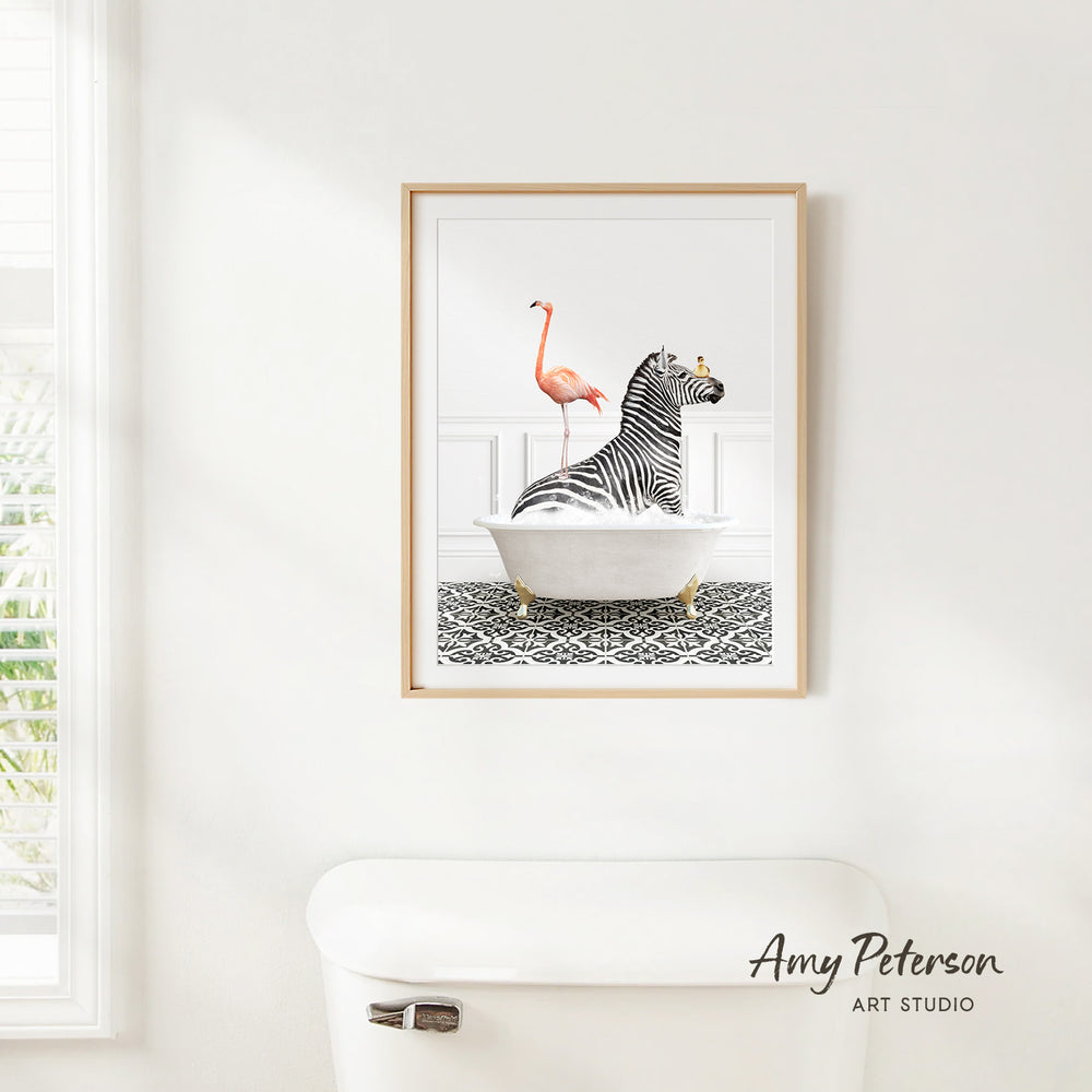 A framed print of a zebra sitting in a bathtub with a flamingo standing on its back, against a white wall.